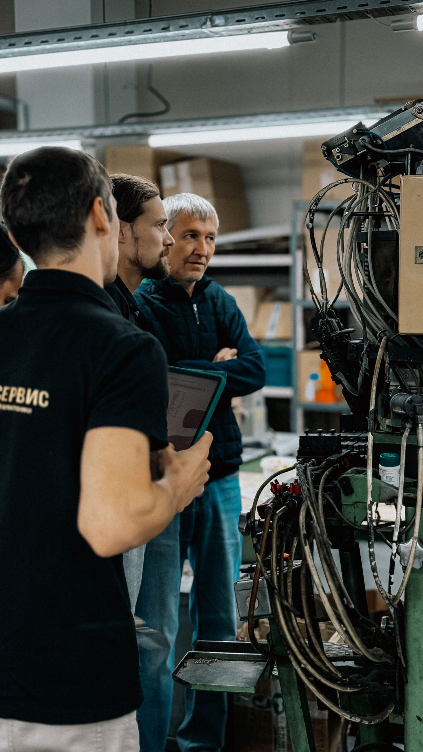 Trois professionnels discutent autour d’une machine dans un environnement industriel